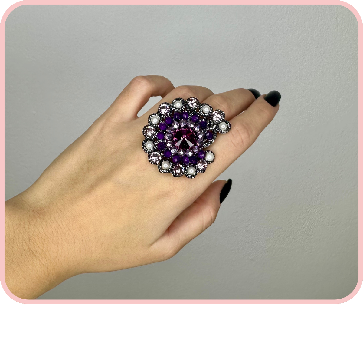 Anelli - New Collection: a hand showcasing a large purple and silver ring with intricate details.