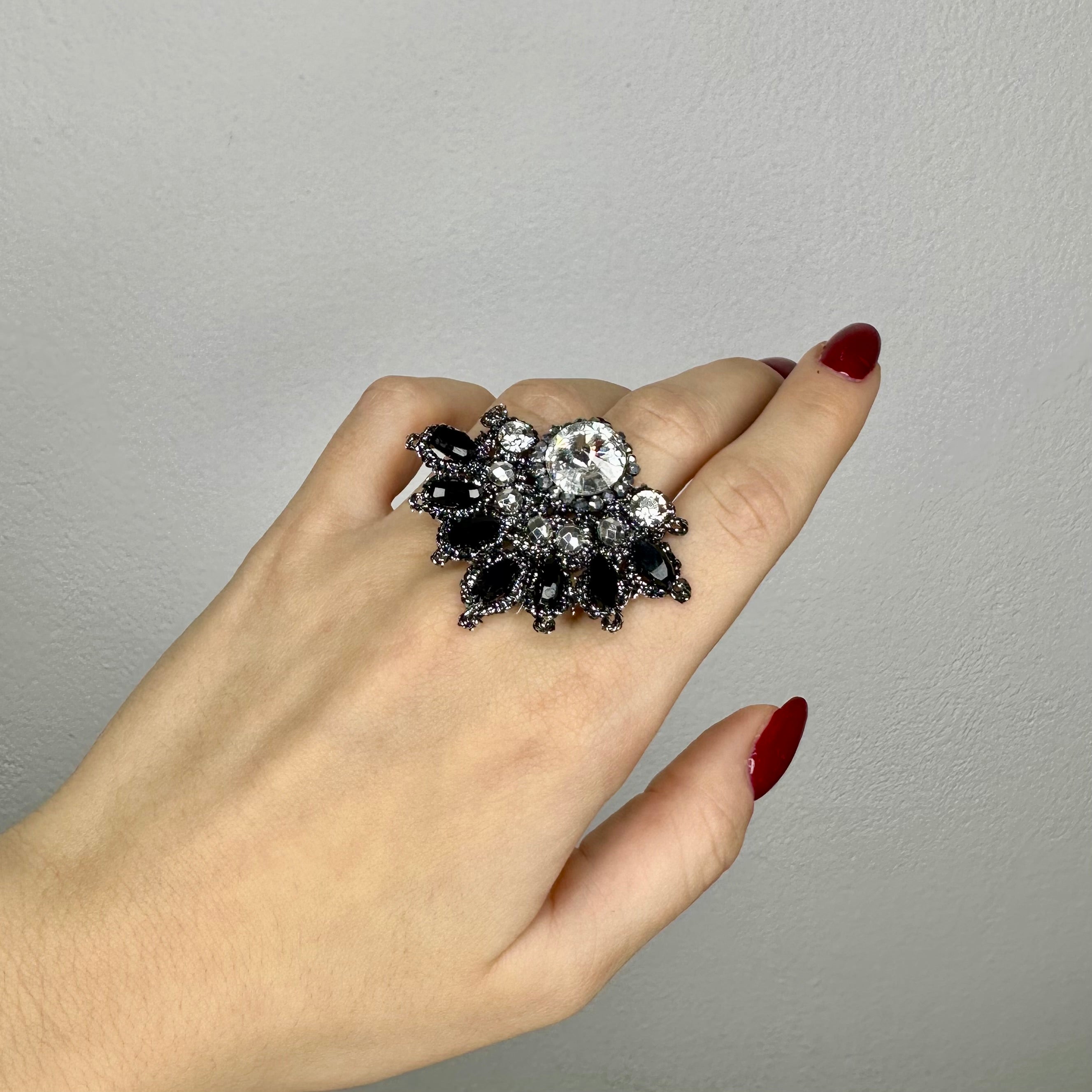 Anello Miró in acciaio con medaglia in pizzo chiacchierino e cristalli, indossato su una mano.