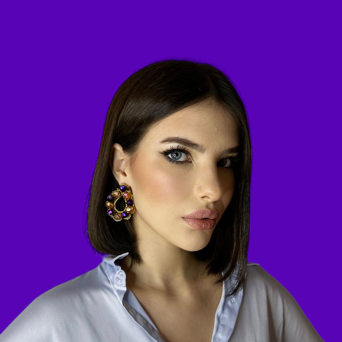 Modella che indossa Orecchini a Goccia in Cristalli su sfondo viola.