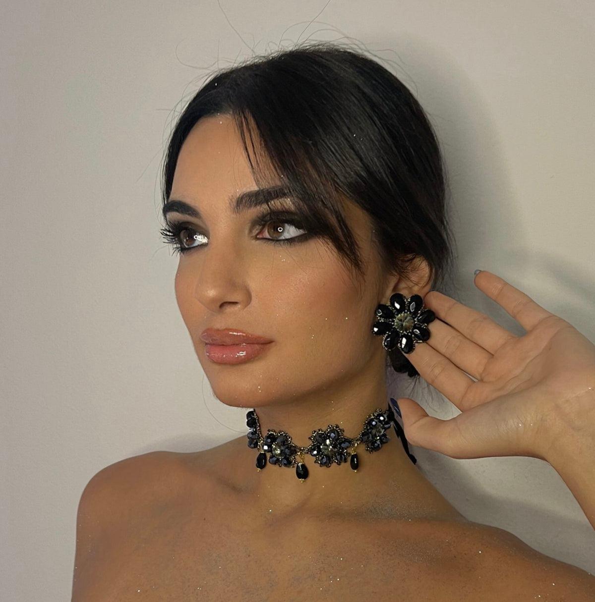 Modella che indossa orecchini a bottone in un set elegante con collana abbinata.