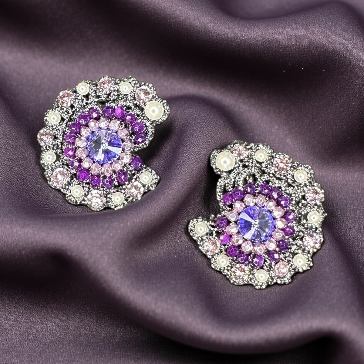 Beautiful Spille brooches featuring purple gemstones on elegant fabric.