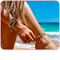 Woman wearing stylish cavigliere and bracelets at the beach, showcasing summer jewelry.