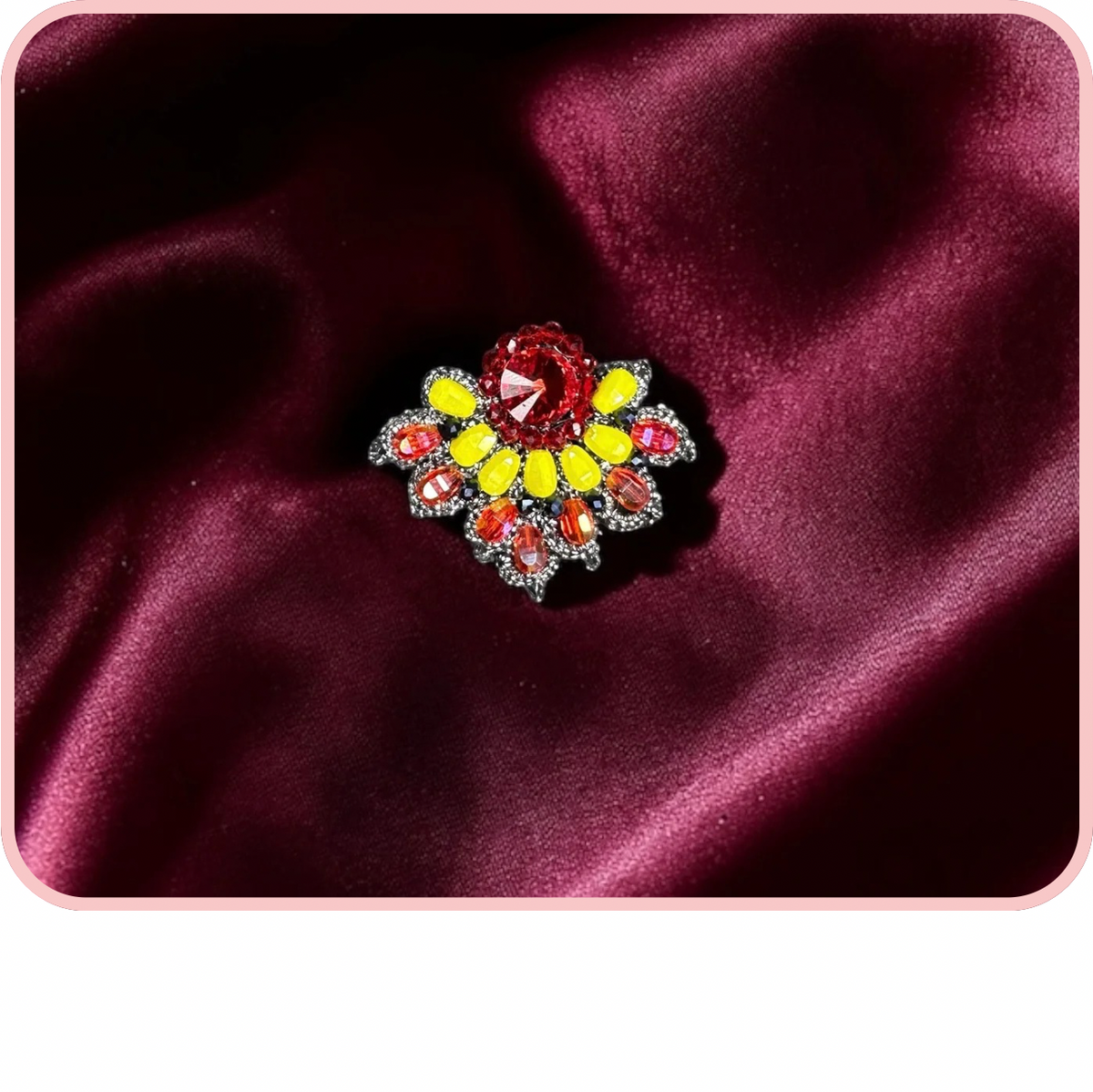 Spille - Spring New Collection colorful brooch with red, yellow, and orange gemstones on a satin background.